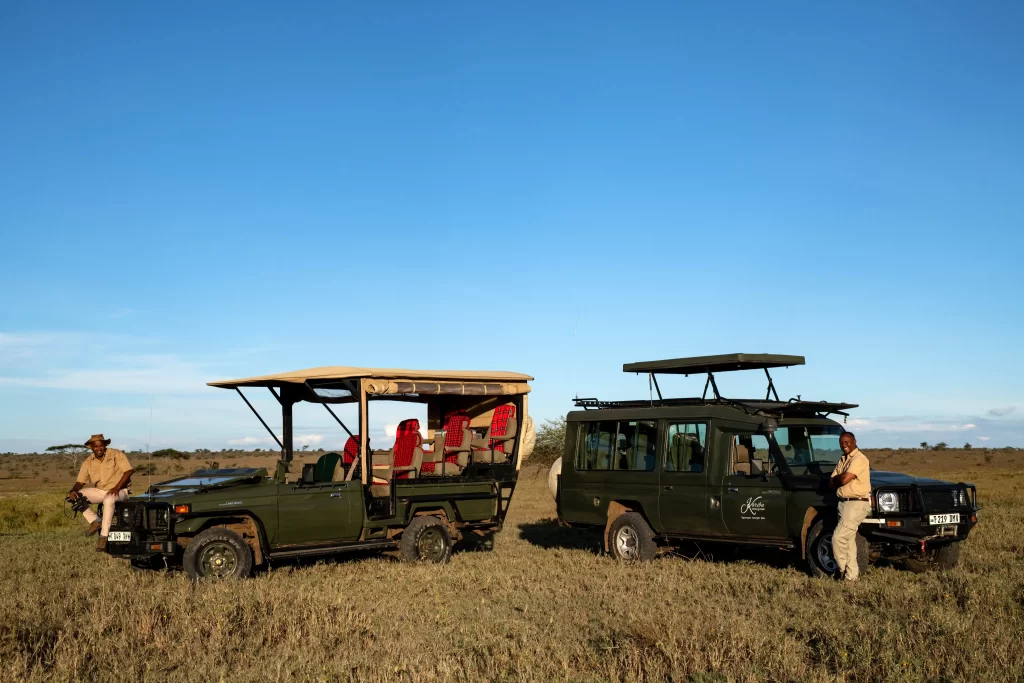 Serengeti woodlands camp tour drivers leaning on the trucks in Serengeti National park