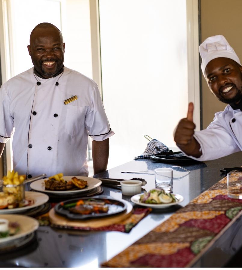 Chefs all smiles while plating food - Karibu camps kitchen